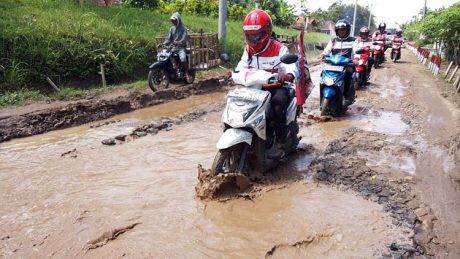 Riders melewati jalan dengan genangan air di Kota Gajah
